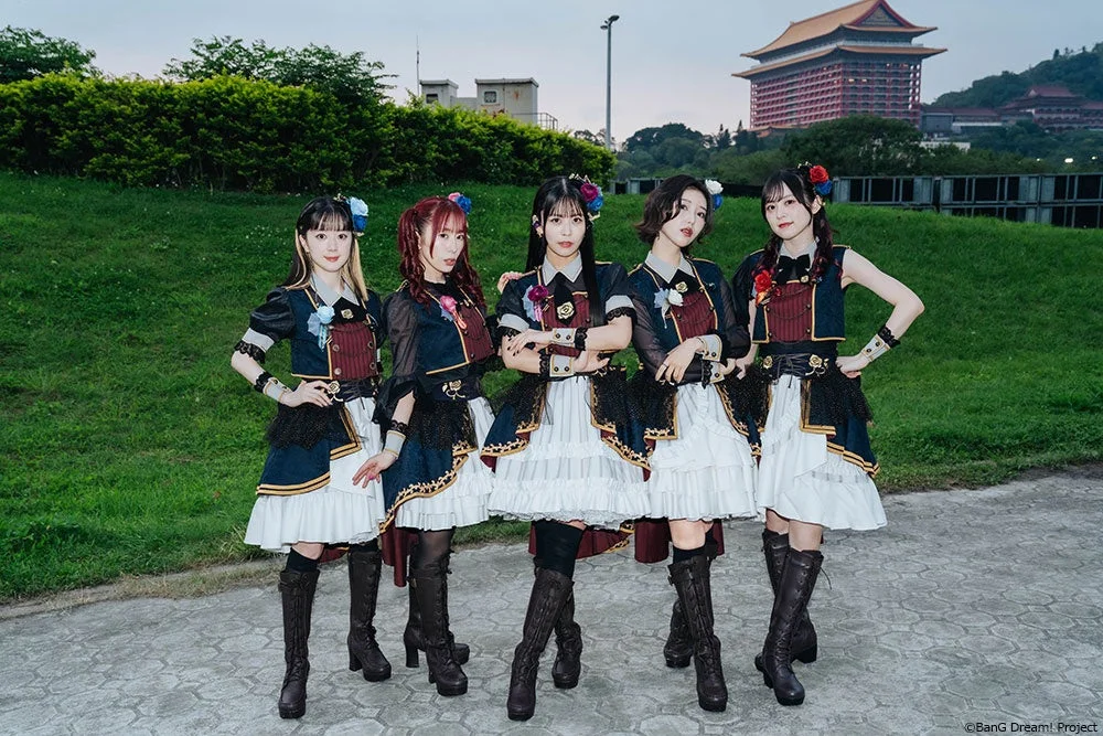 5人の女性アイドルグループが、伝統的な東洋建築の建物(台北グランドホテル)を背景に、お揃いの華やかな衣装でポーズをとっている集合写真