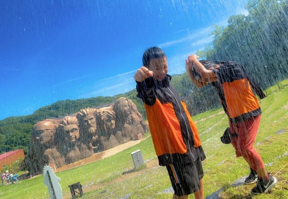 水しぶきを楽しむ子供たちと火影岩